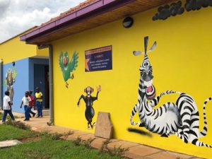 A bright yellow building wall with painted cartoon animals