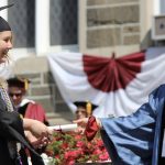 A graduate receiving a degree from Interim Dean Akane Zusho, Ph.D.