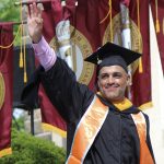 A graduate waving.