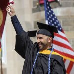 A graduate holding up a diploma.